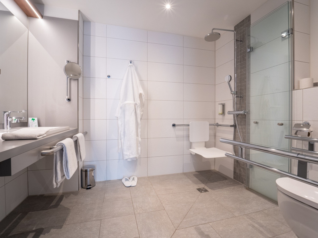 Im barrierefreien Bad kommt man auch mit einem Rollstuhl zurecht - Bad mit unterfahrbarem Waschtisch und großem Spiegel - © Johanniter-Hotel Regensburg gGmbH