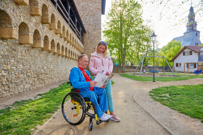 Rollstuhlfahrer mit Begleitung sieht sich Stadtplan an der Stadtmauer in Alzey an - Stadtmauer in Alzey - © Tourist Information Alzey | Robert Dieth Rollstuhlfahrer mit Begleitung sieht sich Stadtplan an der Stadtmauer in Alzey an - Stadtmauer in Alzey - © Tourist Information Alzey | Robert Dieth